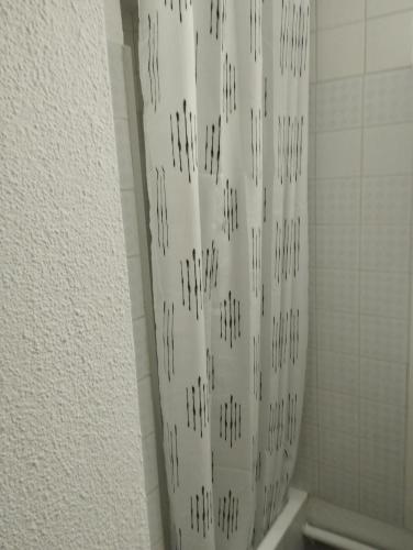 La salle de bains est pourvue d'un rideau de douche et d'un mur en carrelage. dans l'établissement Appartement Vue mer Le Sunset, au Cap d'Agde