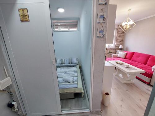 Cette petite chambre comprend un canapé rose et un miroir. dans l'établissement Apartman Hedonia, à Višegrad