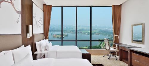a hotel room with two beds and a desk and a large window at The Westin Kolkata Rajarhat in Kolkata