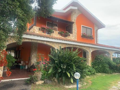 an orange house with plants and flowers in front of it at Il Bouganville in Oristano