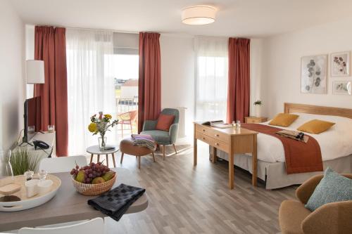 Habitación de hotel con cama y sala de estar. en DOMITYS LES CERNEAUX en Hazebrouck