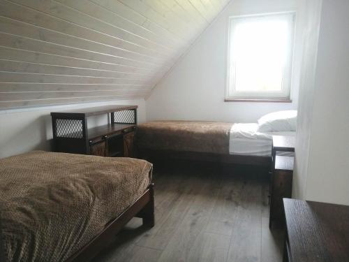 a small room with two beds and a window at Domek całoroczny na mazurach in Orzysz