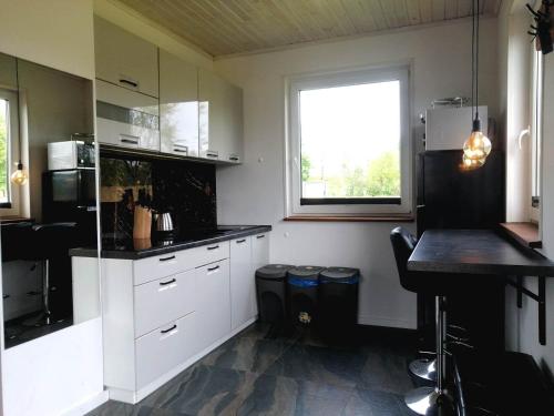 eine Küche mit weißen Schränken, einem Tisch und einem Fenster in der Unterkunft Domek całoroczny na mazurach in Orzysz