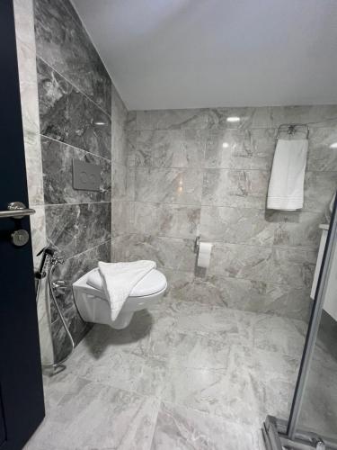 a bathroom with a toilet and a tiled wall at Melissa Suite in Trabzon