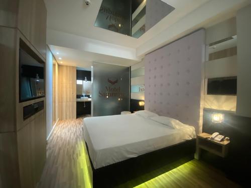 a bedroom with a large white bed and a bathroom at Drops Palhoça Motel in Palhoça