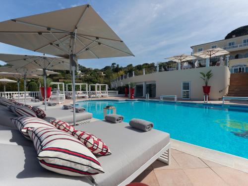 a pool with chaise lounge chairs and an umbrella at Althoff Hotel Villa Belrose in Saint-Tropez