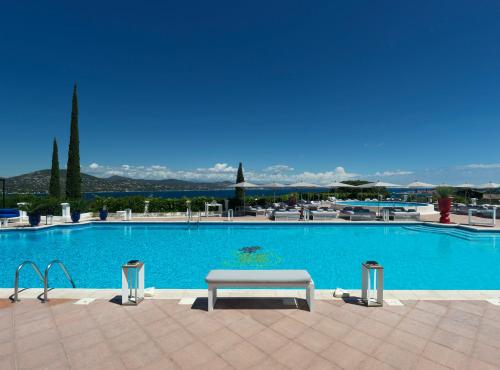 a large swimming pool with a bench in front of it at Althoff Hotel Villa Belrose in Saint-Tropez