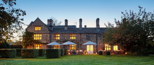 a large stone house with lights on in the yard at The Peacock at Rowsley in Great Rowsley