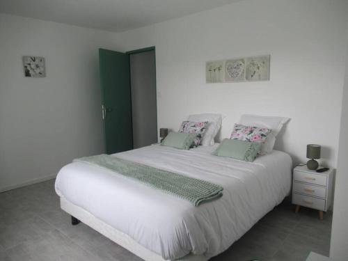 une chambre avec un grand lit blanc avec des oreillers verts dans l'établissement Gîte la Chaumette appartement Emeraude, à Villeuneuve-de-Berg