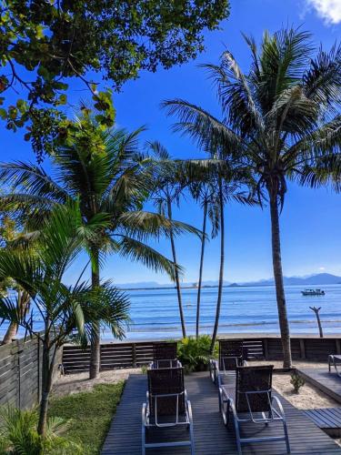 a boardwalk leading to the beach with chairs and palm trees at Pousada Mar e Cia in Ilha do Mel