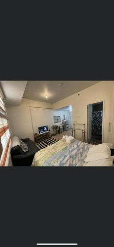 a bedroom with a bed and a living room at Khentdrick's Place at Holland Park Southwoods in Biñan