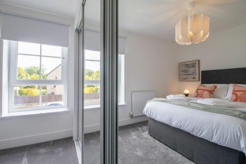 a bedroom with a bed and a large window at The Winnoch - modern 2 bed flat in Lochwinnoch