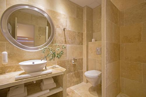 a bathroom with a sink and a toilet and a mirror at ULVF Hôtel Castel Luberon in Apt