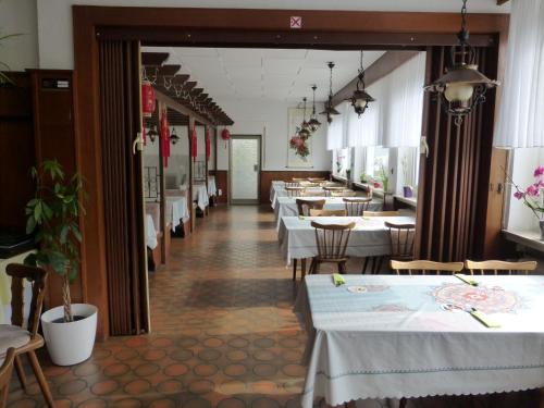 um restaurante com mesas e cadeiras brancas e um corredor em Gasthaus Zum goldenen Löwen em Finkenbach