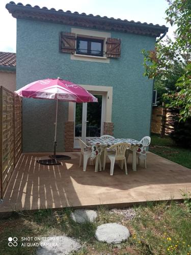 a patio with a table and chairs and an umbrella at Les cyprès in Lagorce