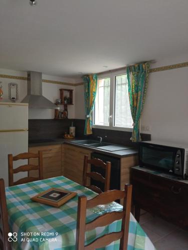 une cuisine avec une table et une cuisine avec une table et des chaises dans l'établissement Les cyprès, à Lagorce