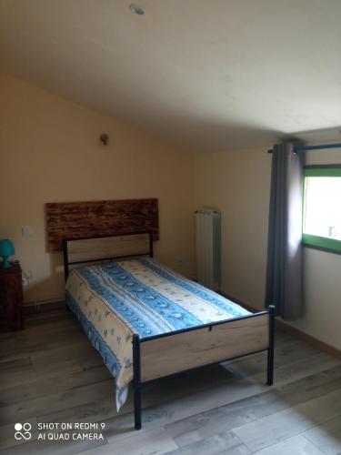 een slaapkamer met een bed in een kamer met een raam bij Les cyprès in Lagorce