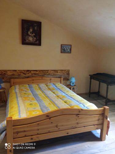 een slaapkamer met een bed met een houten frame bij Les cyprès in Lagorce