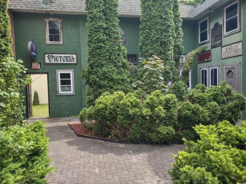 a green building with bushes in front of it at The King George Inn in Cobourg
