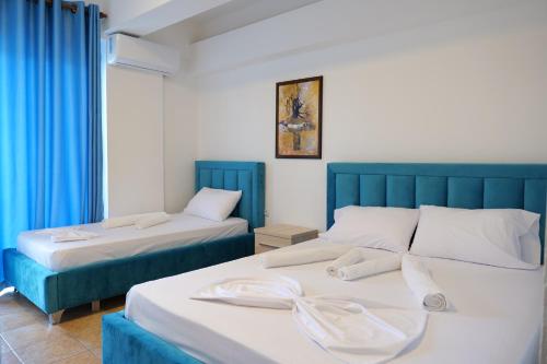 Mema Hotel في هيماري: سريرين في غرفة ذات ستائر زرقاء