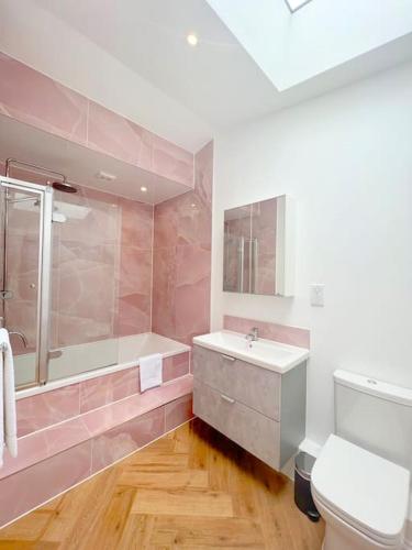 a bathroom with a tub and a sink and a toilet at Orchard Cottage - Kent in Lyminge
