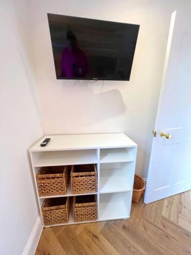 a tv hanging on a wall above a white cabinet at Orchard Cottage - Kent in Lyminge