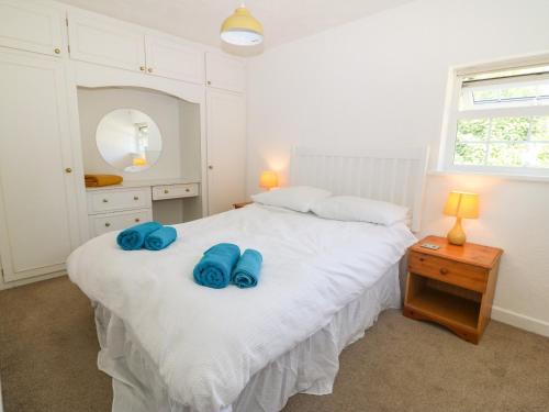 een slaapkamer met een wit bed en blauwe handdoeken. bij Min Y Mor in Criccieth