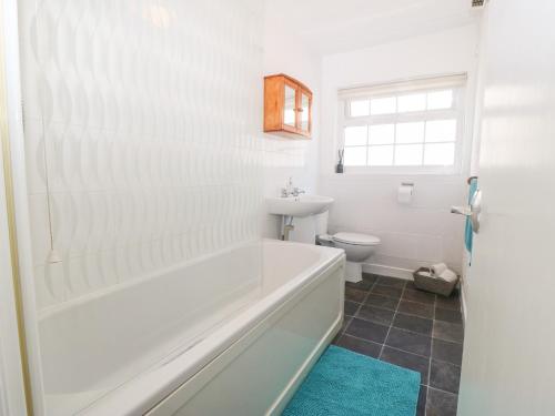 een witte badkamer met een bad en een toilet bij Min Y Mor in Criccieth