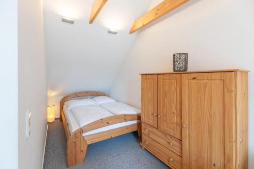 een slaapkamer met een houten bed en een houten kast bij Haus zu den Halligen in Bredstedt