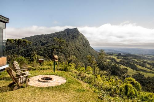 a bench sitting in the grass with a mountain in the background at Caminho das Nuvens - Cabanas de Montanha in Bom Retiro