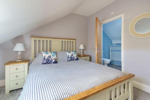 a bedroom with a bed with blue and white sheets at 1 Afon y Felin in Abersoch