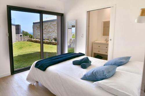 a bedroom with a large white bed with blue pillows at Ty Dag - Petite Terre vue mer, spa, plage à 300m in Roscoff