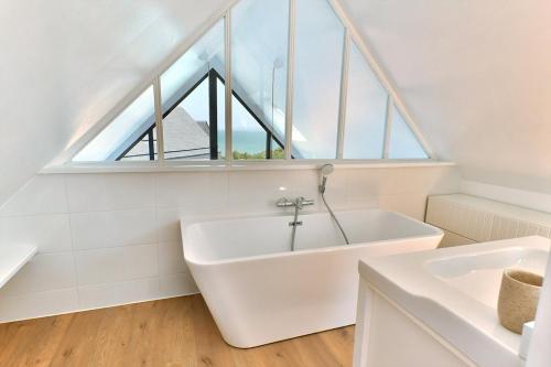 a white bathroom with a large window and a tub at Ty Dag - Petite Terre vue mer, spa, plage à 300m in Roscoff