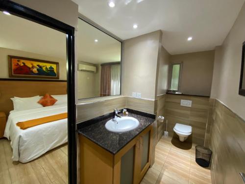 a bathroom with a sink and a bed at La Cour Hotels and Apartments Cooper in Lagos