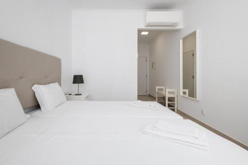 Habitación blanca con cama y espejo en Dunas Hostel & Guesthouse, en Alvor