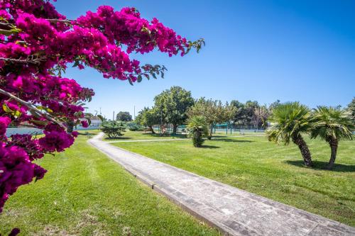 a path in a park with pink flowers and palm trees at The aurora's home in Quartu SantʼElena