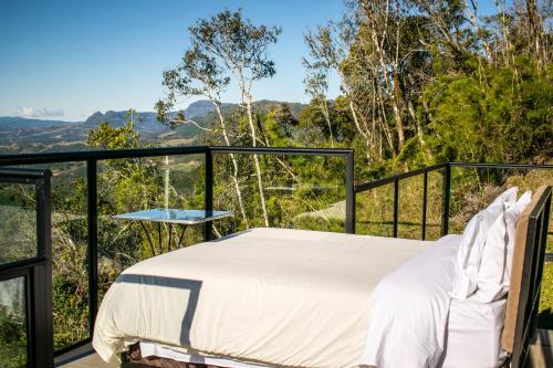 a bed on a balcony with a view of the mountains at Caminho das Nuvens - Cabanas de Montanha in Bom Retiro