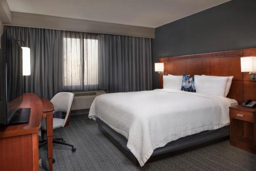 a hotel room with a large bed and a desk at Courtyard Winston-Salem University in Winston-Salem