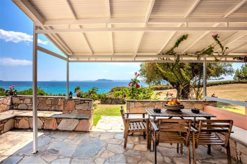 a patio with a table and chairs and the ocean at Alterra Vita Captain's Cabin in Neos Marmaras