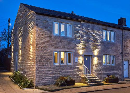 Una casa de ladrillo con luces en el lateral. en The White Hart at Lydgate, en Oldham