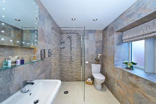 a bathroom with a bath tub and a toilet at The White Hart at Lydgate in Oldham
