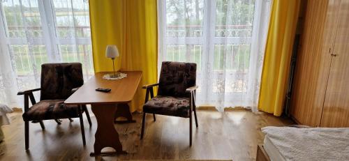 a room with a table and two chairs in front of windows at Dom Wczasowy Orka in Łazy