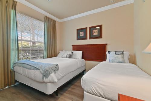 two beds in a hotel room with a window at Near Disney w/ pool-3BR/2BA-Spacious & Cozy Condo in Davenport