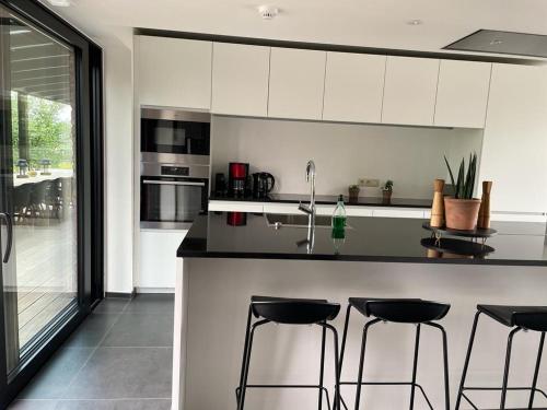 a kitchen with white cabinets and black counter stools at Le Vieux Moulin in Marche-en-Famenne