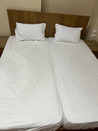 a large white bed with two pillows on it at Paris east in Cairo
