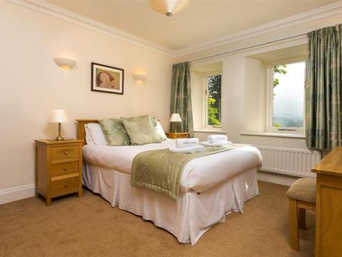 a bedroom with a large bed and two windows at 2 Hart Head Barn in Ambleside