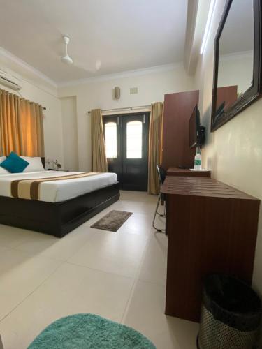 a bedroom with a bed and a desk with a television at Krishna Kunja " A Quiet & Peaceful Stay " in Kolkata