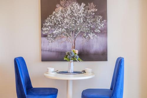 a table with two blue chairs and a vase with flowers at Batumi River Source in Batumi