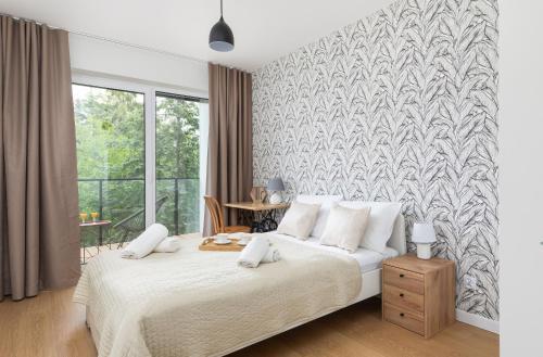 - une chambre avec un lit blanc et une grande fenêtre dans l'établissement Wellness Resort & SPA Apartments Dziwnów Riverfront by Renters, à Dziwnów