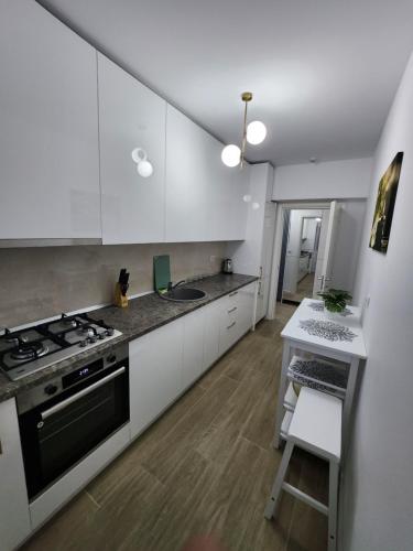 a kitchen with white cabinets and a stove and a table at DeLux Apartments with Terassa in Towers Ever Green in Iaşi